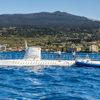a blue boat on a body of water with a mountain in the background