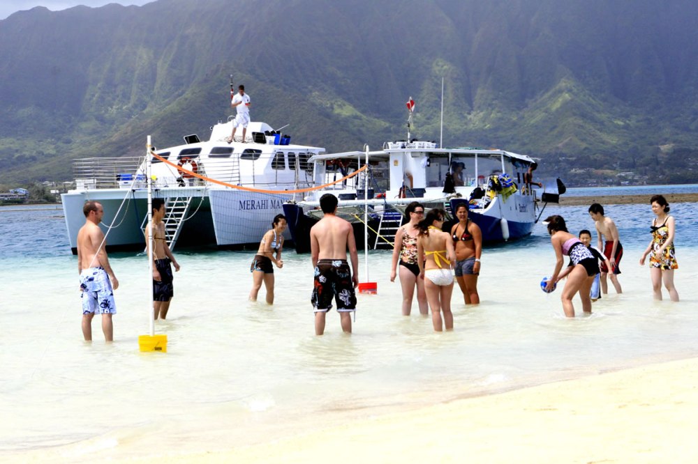 a group of people on a beach with a mountain in the background