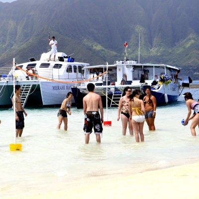 a group of people on a beach with a mountain in the background