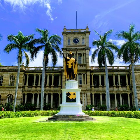 a large clock tower in the middle of a garden