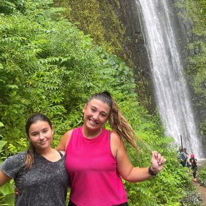 a young girl standing next to a forest
