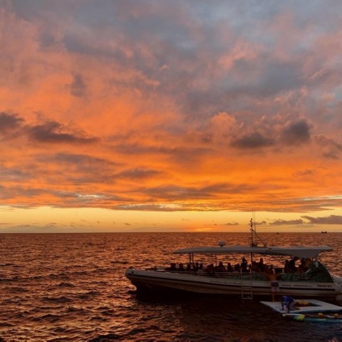 a sunset behind a boat on a body of water