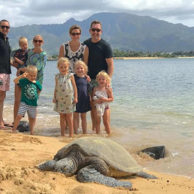 family posing with a honu on the beach