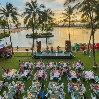 a group of people sitting at a table with a vase of water