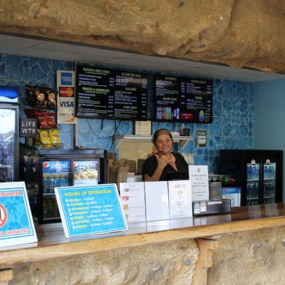 Concession stand with menu, signs, and woman smiling behind the counter.