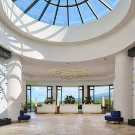 Spacious lobby with circular skylight, white columns, and decorative blue accents.