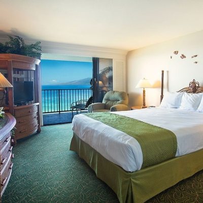 Hotel room with bed, ocean view, balcony, and tropical decor.