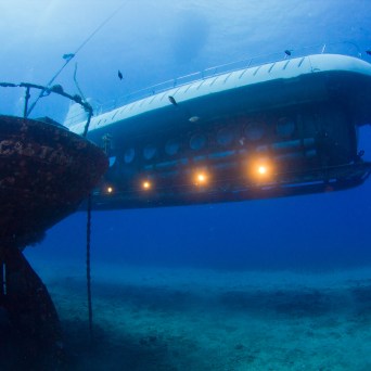 Submarine underwater near a sunken shipwreck.