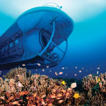 Submarine underwater above coral reef with colorful fish.