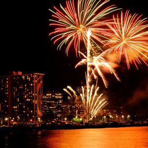Colorful fireworks burst over city skyline at night.