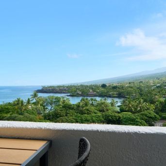 Coastal view from a balcony overlooking ocean and lush greenery.