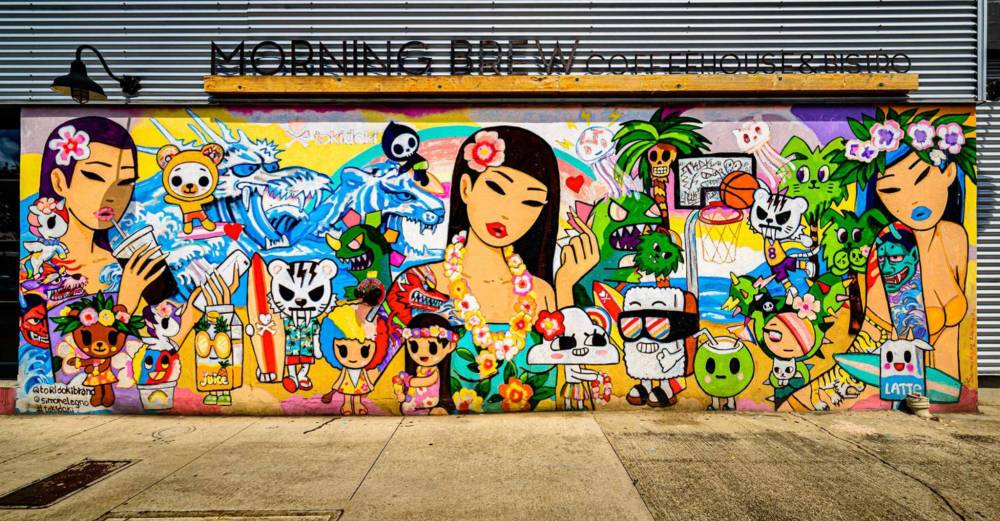 Colorful mural with cartoon characters, stylized women, and various animals on a building wall.